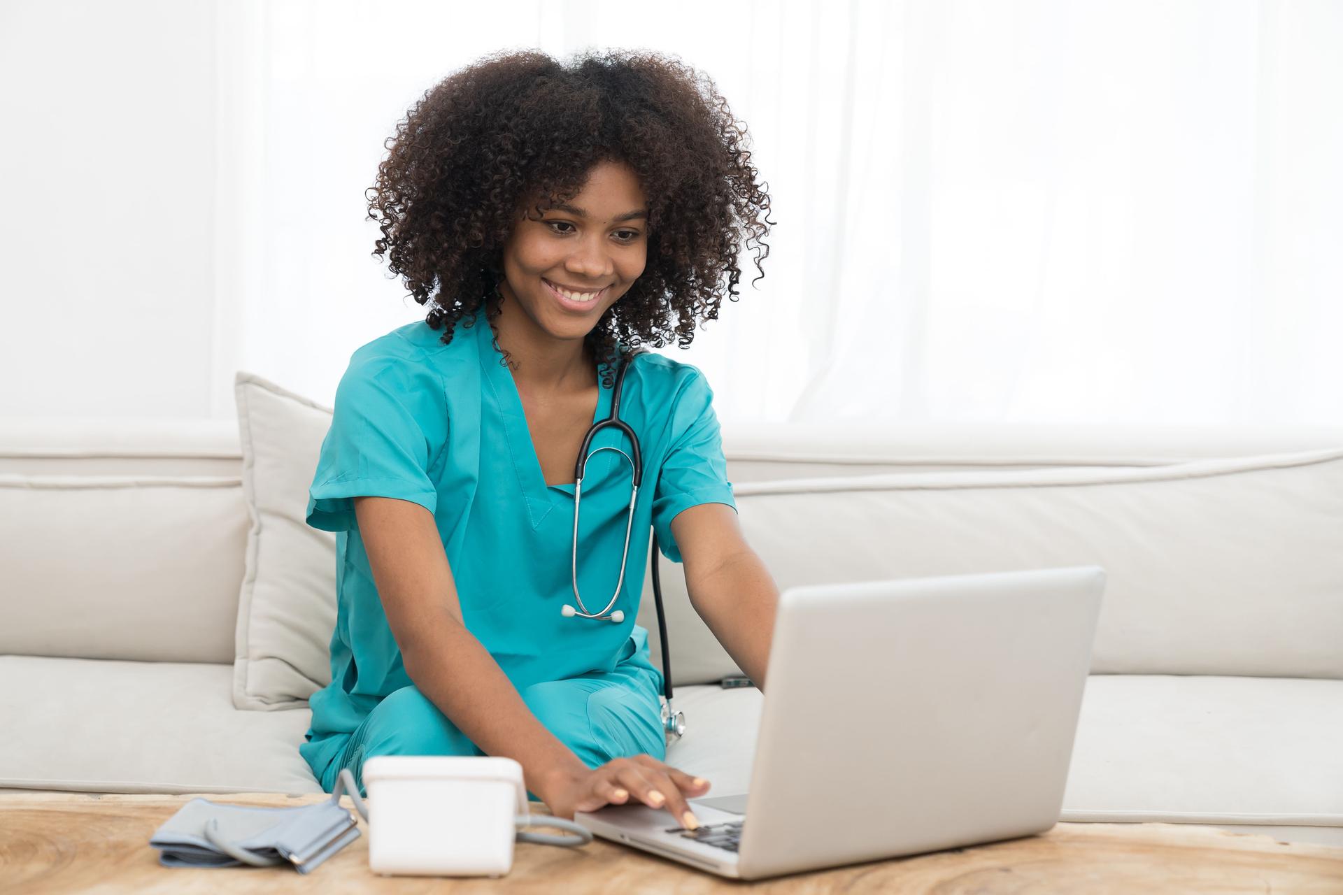Happy young nurse working with laptop computer in the hospital. Smiling young female doctor or young nurse giving advices to the patients online by laptop computer at home