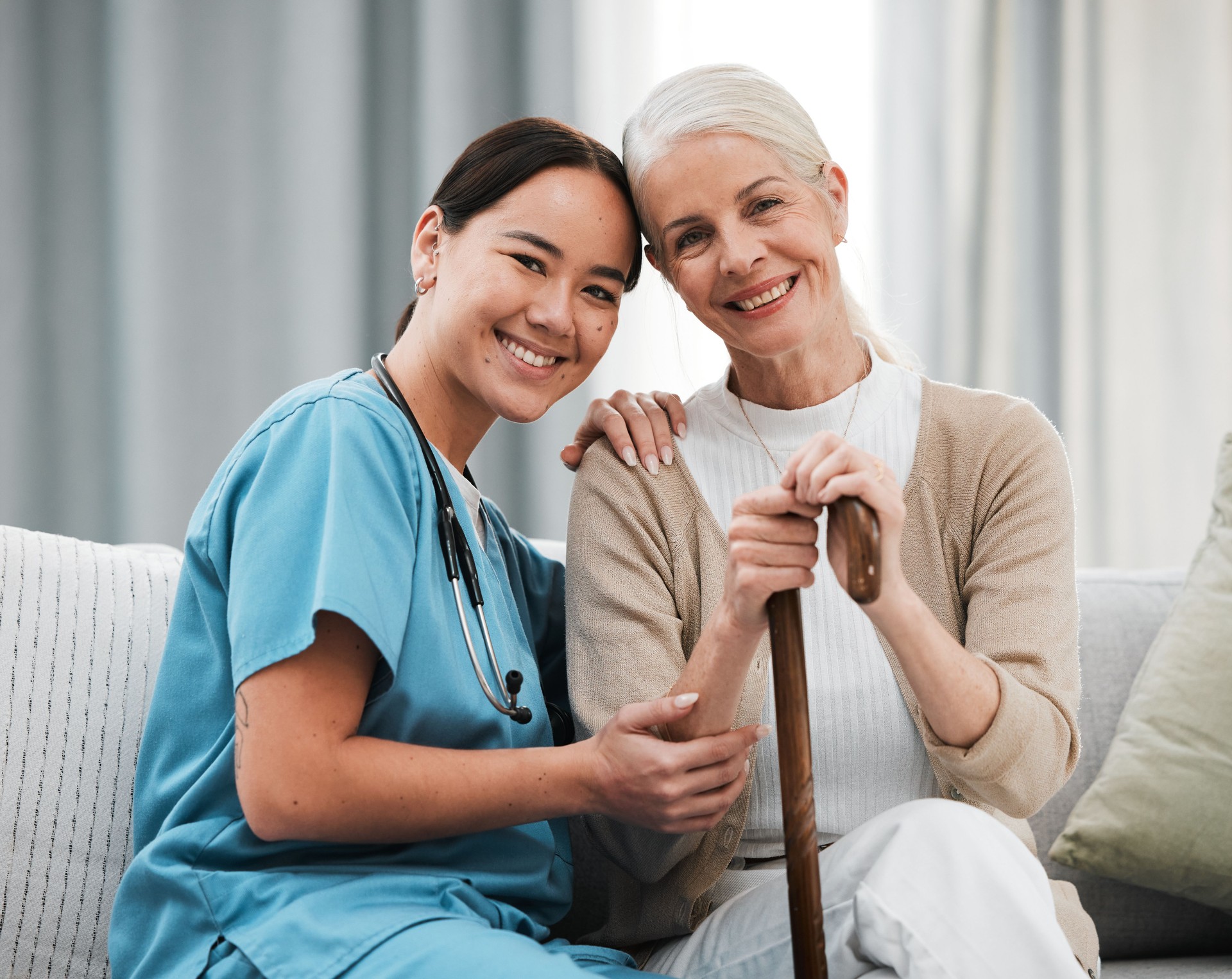 Nurse, elderly woman and sofa for portrait, walking stick and smile together with happiness, chat and care. Senior patient, asian doctor and couch with helping hand, happy and connection for support